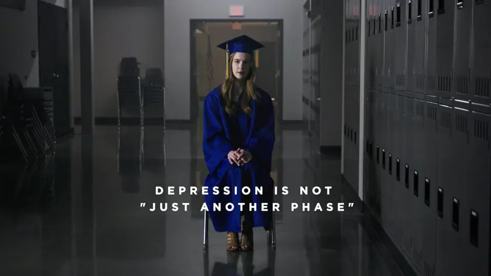 A graduate in cap and gown sitting in the same hallway.
