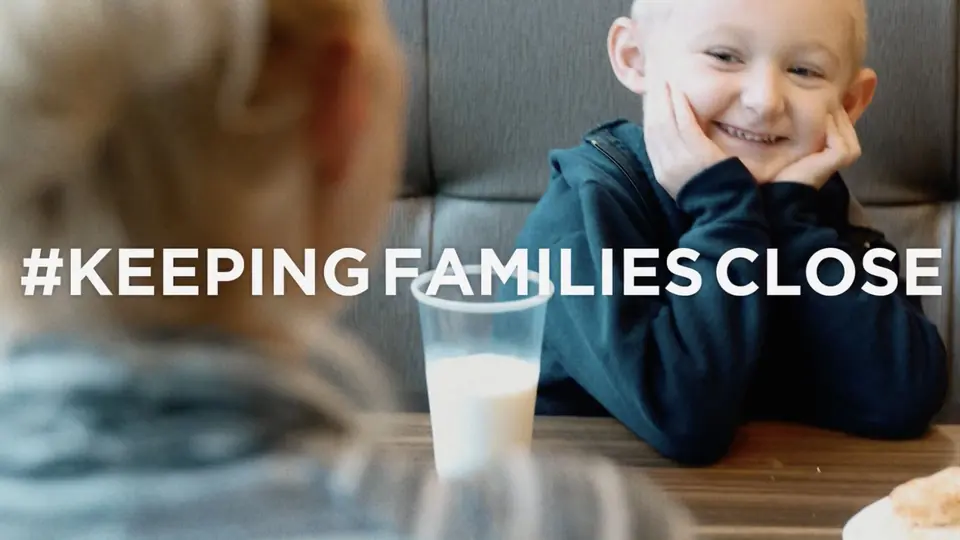 A smiling child at a table, with the line Keeping Families Close.