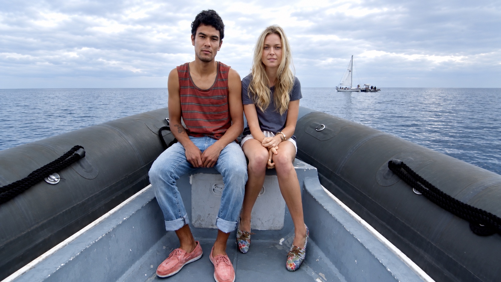 A couple sitting on the bow of an inflatable boat.
