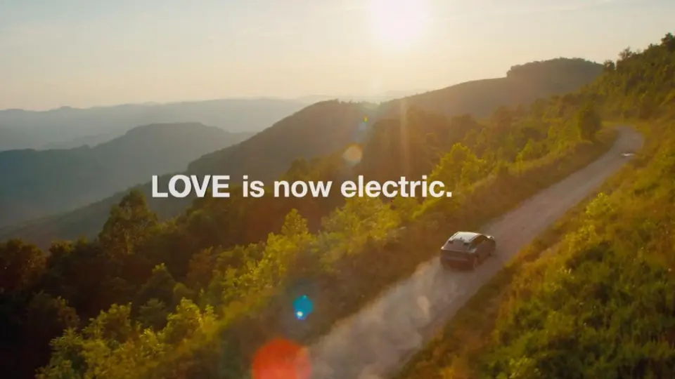 A mountain road at sunset with the line: Love is now electric.