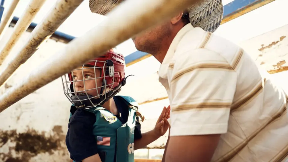 An adult fitting a helmet on a young rider.